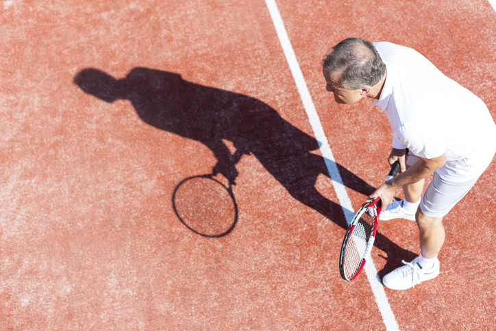 older man getting ready to serve tennis with shoulder problems
