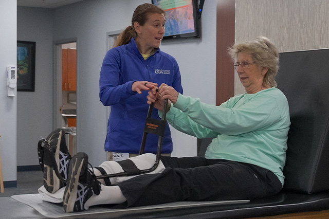 orthopedic doctors from sos syracuse orthopedic specialists physical therapist helping patient stretch leg