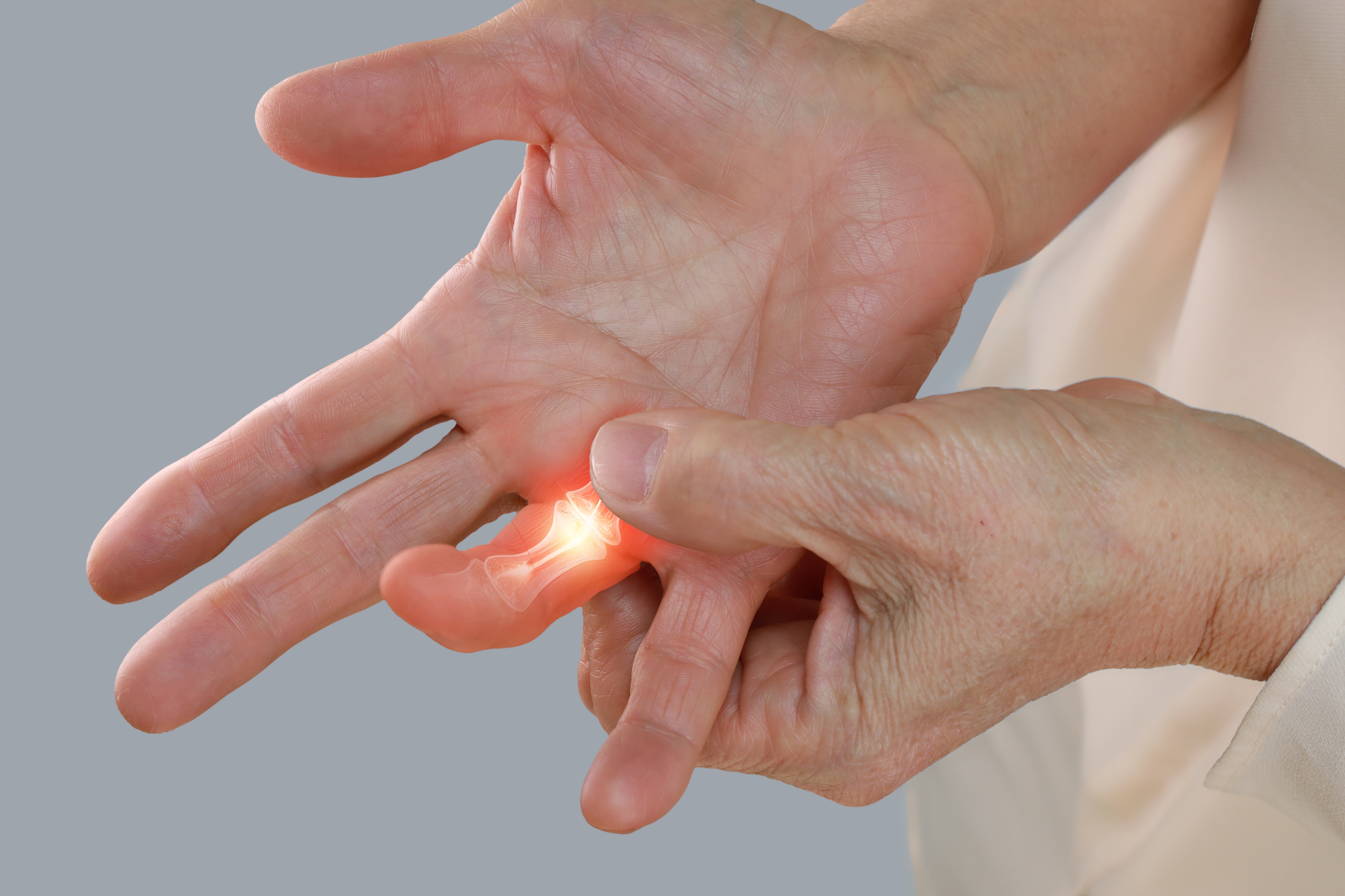 A person grabs on to their ring finger due to joint pain.